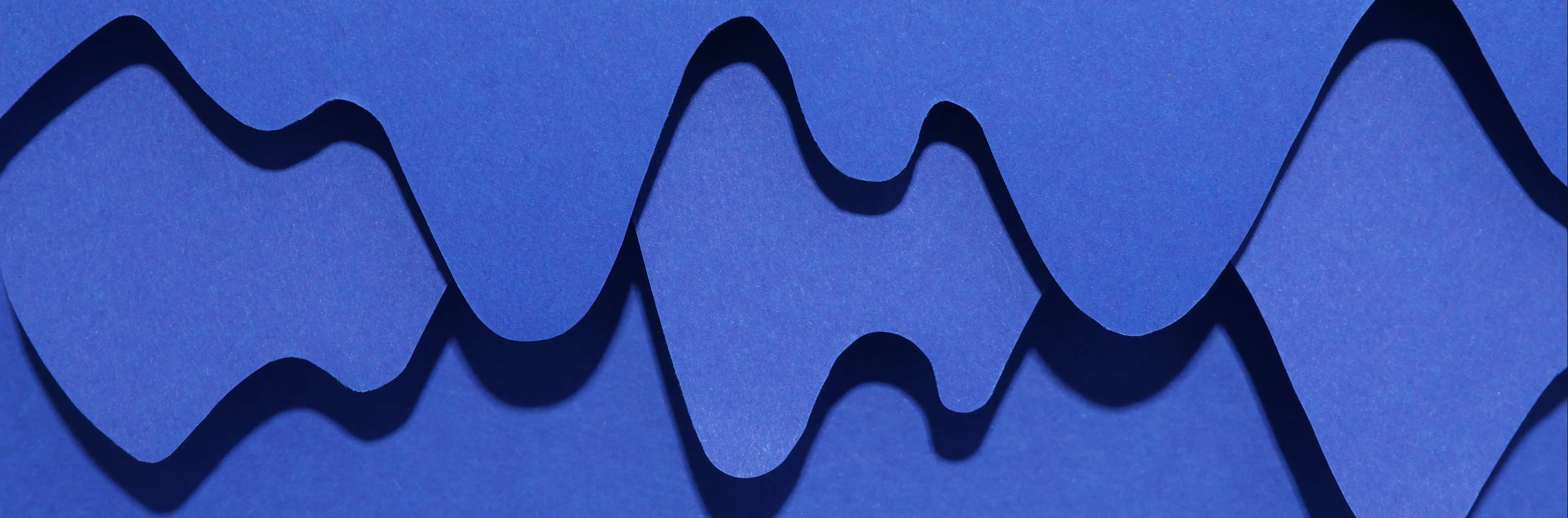 Overlapping blue paper-cut wave layers on a dark background