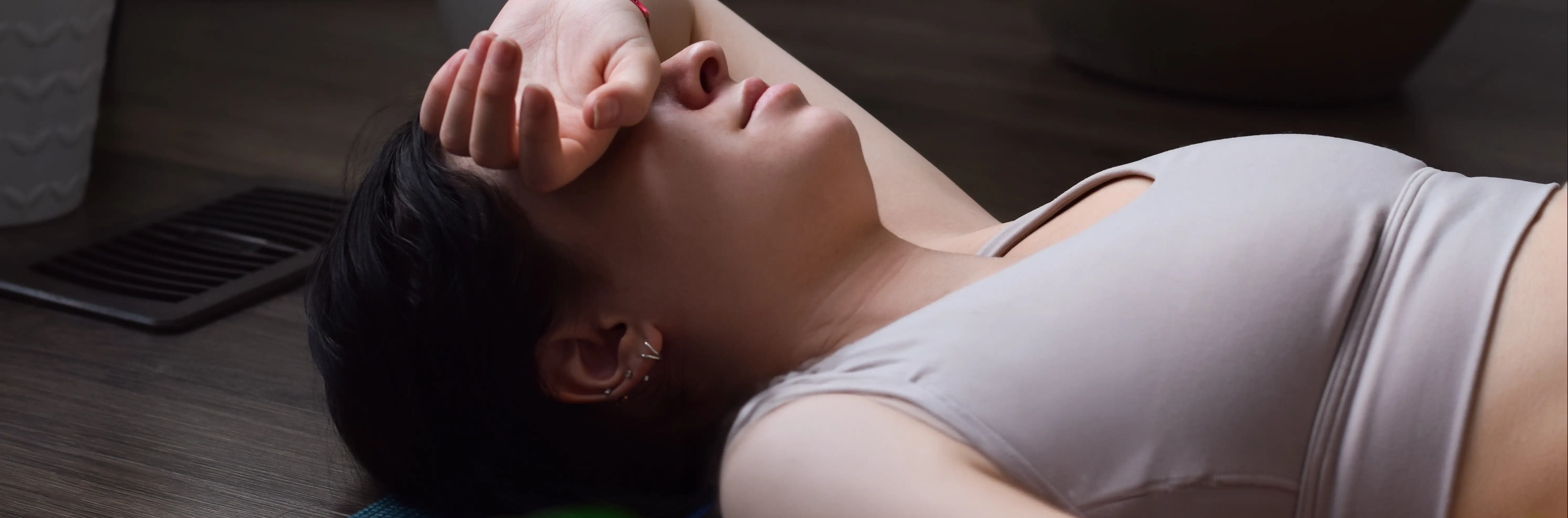 A woman lying on her back with one hand covering her eyes